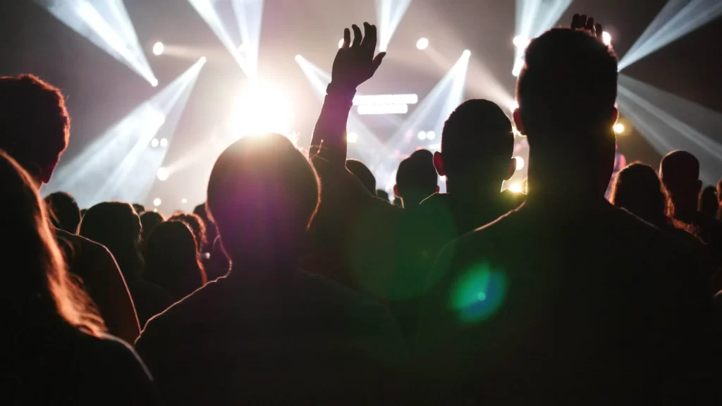 Várias pessoas assistindo a um festival com forte iluminação